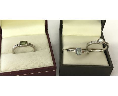 3 silver stacking rings each set with a semi precious stone. All bands have decorative design. One set with baguette cut peri