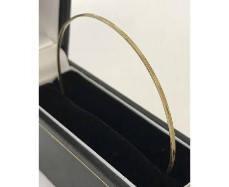 A slim 9ct gold bangle with diamond cut decoration to outside rim. Diameter approx. 7cm. Total weight approx. 2.7g.