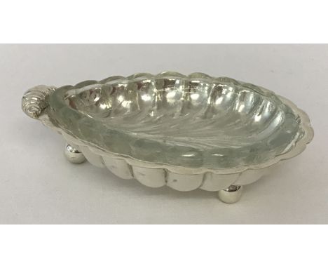 A silver plated shell shaped butter dish raised on tripod ball feet, complete with glass liner.  Approx. 13.5cm x 10cm x 3.5c
