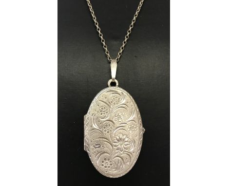 A large vintage oval silver locket with engraved floral detail to front. Bark effect decoration to back, on a 18" belcher cha