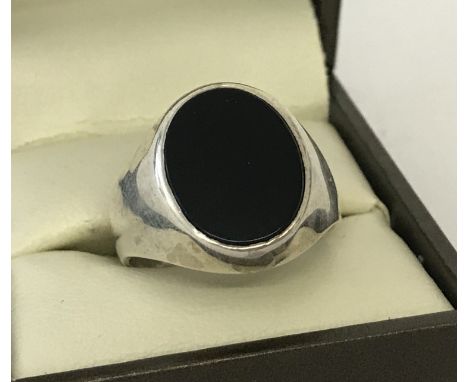 A men's silver signet ring set with an oval black onyx stone. Size T.  Total weight approx. 6.9g.