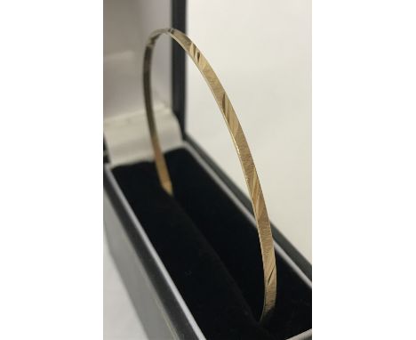 A slim gold bangle with diamond cut decoration to outside rim. Tests as 9ct gold. Diameter approx. 6.5cm. Total weight approx