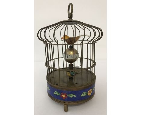 An ornamental wind up birdcage clock with cloisonné panel to base. The cage features two small feathered birds which rotate w