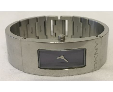 A ladies stainless steel bracelet watch by DKNY. Blue metallic face with silver coloured hands. DKNY logo to front of case an