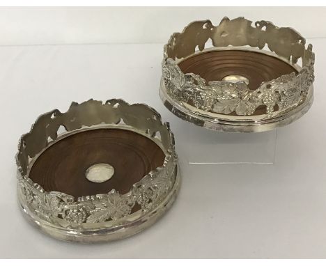 2 heavy silver plated wooden based coasters with grape and vine detail to sides.  Approx. 4.75cm tall x 14.5cm diameter.