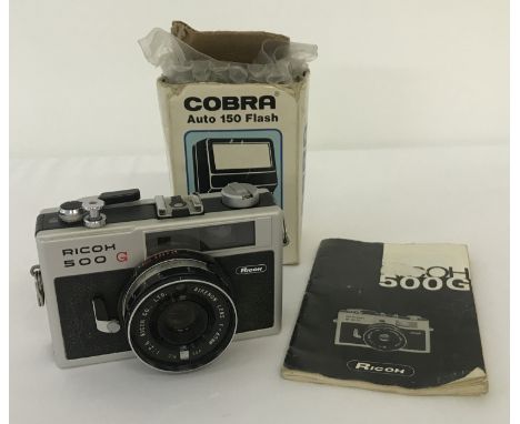 A vintage Ricoh 500G camera, with Rikenon lens, complete with instruction manual. Together with a boxed Cobra auto 150 flash.