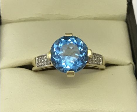 A 9ct gold Swiss blue topaz and diamond dress ring. Central brilliant cut Swiss blue topaz approx. 2.5ct with 8 small round c