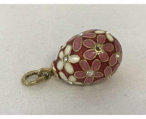 An enamel and clear stone set, flower design egg charm/pendant with silver gilt fixing and bale. Bale fully marked. Approx. 3