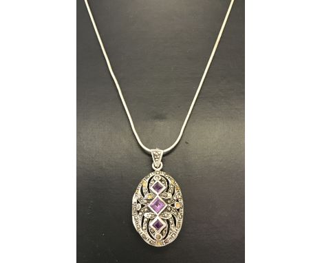 A silver oval locket with pierced work detail to front. Set with square cut amethysts &amp; marcasite's. On a 18" fine snake 