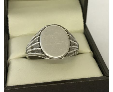 A men's silver signet ring with decoration to shoulders and empty oval shaped cartouche. Size X.  Total weight approx. 6.8g.