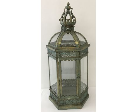 A large green metal ornamental free standing, hexagonal lantern. With glass panels, hanging hook and front opening hinged doo