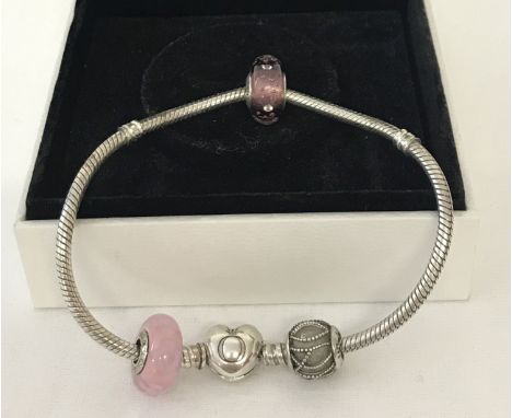 A silver Pandora charm bracelet with heart shaped catch complete with 3 charm beads. Beads comprise: 2 glass beads, one with 