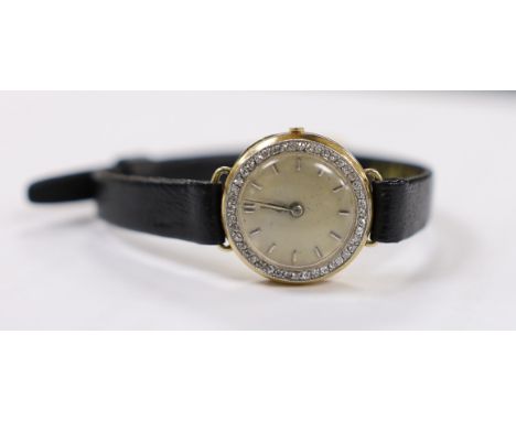A lady's 18k manual wind wrist watch, with diamond set bezel and dial with baton numerals (a.f.), on a leather strap.