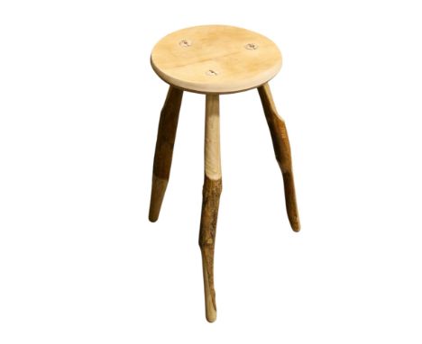 A contemporary wooden stool. The circular top mounted on three naturalistic stick supports, H65cm