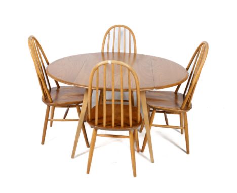 An Ercol circular table and four chairs. Pale wood, the chairs with stick backs, table 113cm x 121cm. 