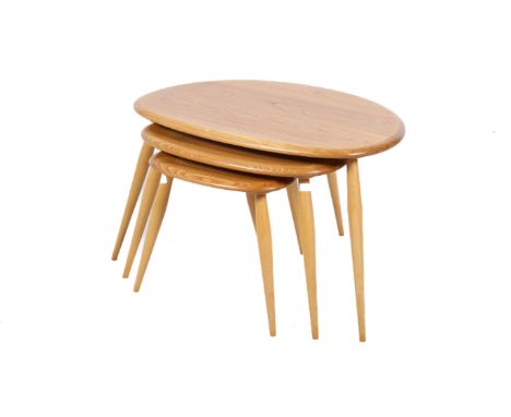 A mid-century Ercol blonde beech and elm nest of tables. The nest of three tables having pebble shaped elm tops raised on tap