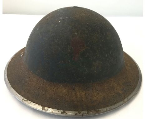 A British WWII MkII steel helmet with hand painted skull and crossbones decal. Oval lining pad and canvas chin strap. From a 