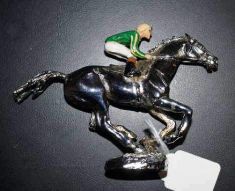 Small white metal model of a racehorse with a cold painted jockey wearing the colours of J P McManus. Said to be a car mascot