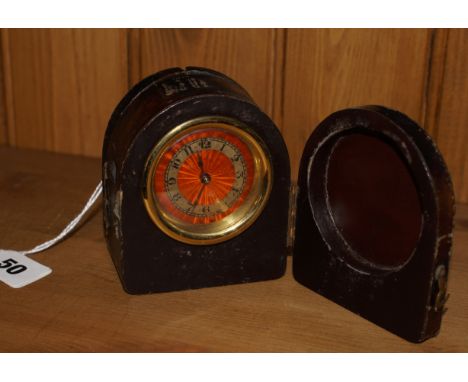 Art Deco travelling clock with engine turned and orange enamelled dial in a leather covered wood case