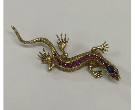 A large ruby and sapphire brooch in the form of a lizard with textured body in 18 carat gold. Approx. 15 grams. Est. £1200 - 