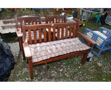 A wooden bench and two matching chairs, with covers and cushions