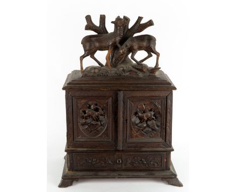 A 19TH CENTURY GERMAN BLACK FOREST TABLE TOP CABINET with carved deer above twin doors with carved mountain goat, opening to 