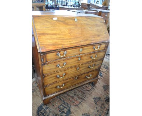 A Georgian mahogany bureau of typical form with full front opening to a fitted interior with small drawers and pigeon holes, 