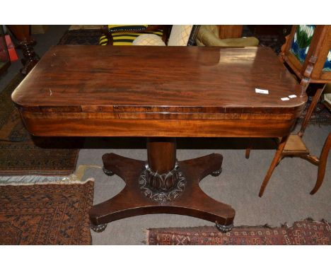 An early Victorian mahogany card table with folding leather lined top over a turned column, platform base and short bun feet,