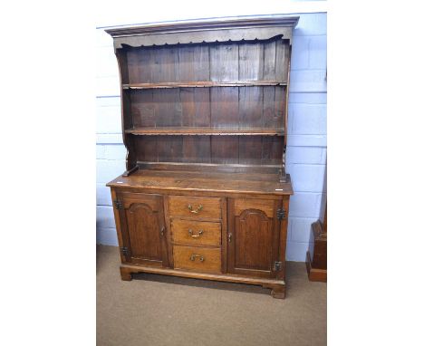 A small oak dresser in the George III style, the top section with moulded cornice over two shelves, the base with three centr