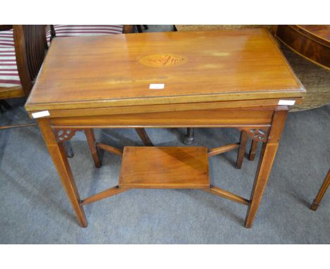 An Edwardian mahogany card table, the top inlaid with shell decoration and fitted with a baize lined interior, raised on tape