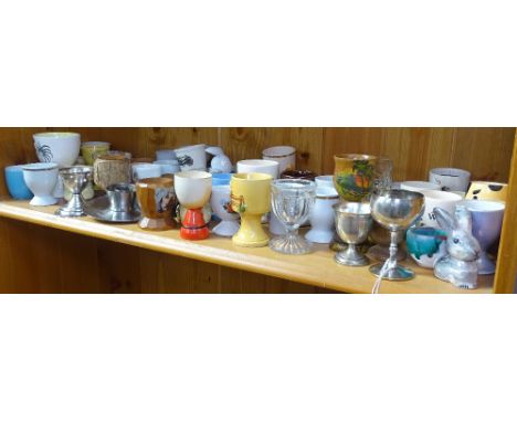 A shelf of Vintage glass, metal, and porcelain egg cups 