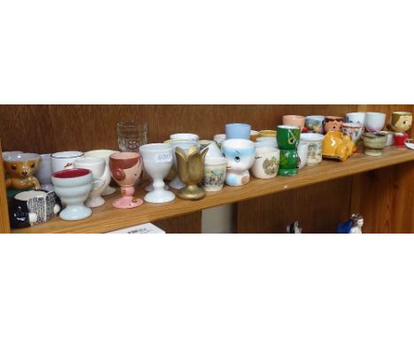 A shelf of Vintage wooden, porcelain, and glass egg cups 