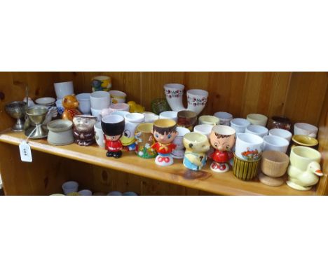 A shelf of Vintage metal, porcelain, plastic, and wooden egg cups 