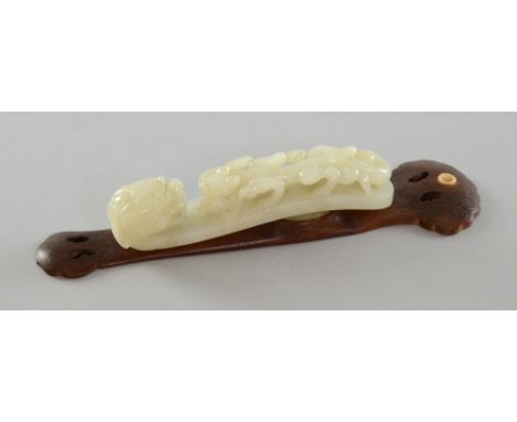 Chinese white jade belt hook carved as a horned dragon and a smaller bifid dragon, 12.5cm long, on carved hardwood and inlaid