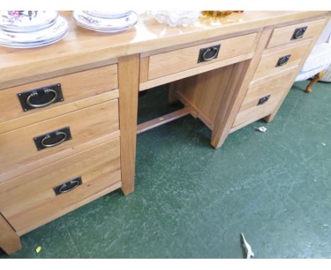 LIGHT OAK MODERN DESK WITH SEVEN DRAWERS AND METAL HANDLES.