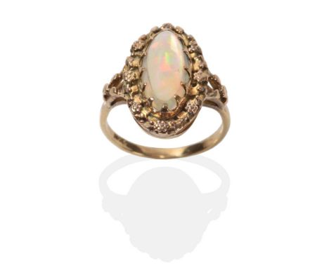 An Arts & Crafts Opal Ring, an oval opal in a claw setting within a border of small flower heads, to forked shoulders, finger