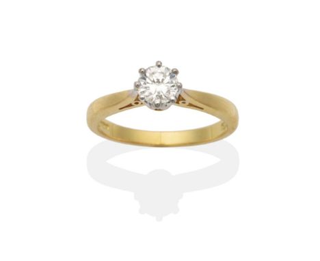 An 18 Carat Gold Diamond Solitaire Ring, a round brilliant cut diamond in a white claw setting, to yellow knife edge shoulder