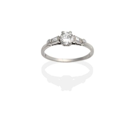 A Diamond Solitaire Ring, a round brilliant cut diamond in a claw setting to shoulders each set with a baguette cut and an ei