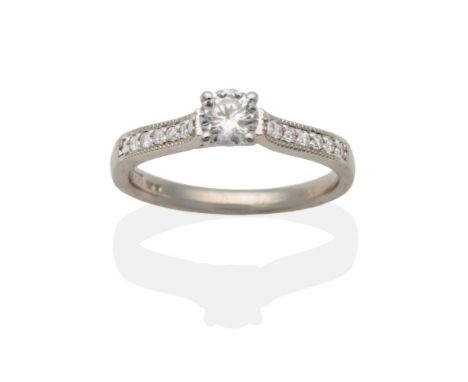 An 18 Carat White Gold Diamond Solitaire Ring, a round brilliant cut diamond in a claw setting, to diamond set shoulders on a