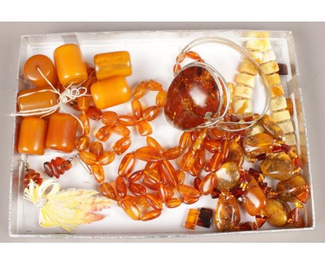 An amber set white metal bangle along with a quantity of amber coloured beads.  