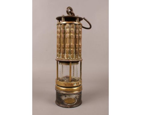 A brass Miner's lamp by 'Wolf Safety Lamp Co of America' with cylindrical lens and swing. H: 30cm.  Condition good. Some mino