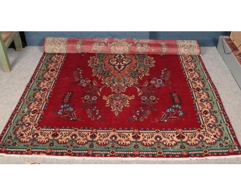 A vintage red ground Persian Tabriz carpet. With bespoke medallion design surrounded by green and cream borders. (293cm x 206