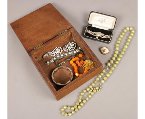 An oak box of costume jewellery. Including white paste stone set cocktail watch, earrings, vintage jewellery, etc.  