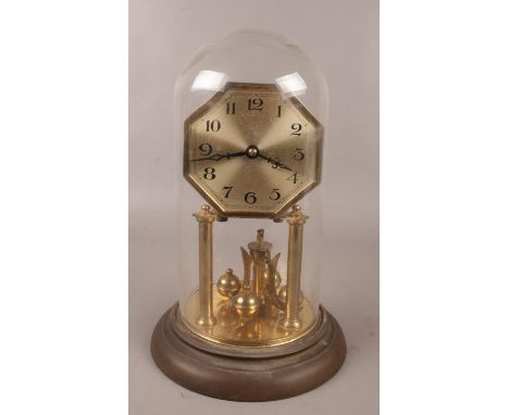 A German brass torsion clock under glass dome. Octagonal dial and Arabic numeral markers.  