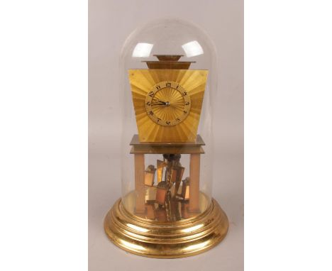An Art Deco brass torsion clock, under glass dome. (31cm).  Pendulum snapped. Chips to base of glass. Generally good conditio