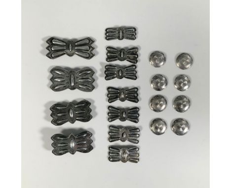 A collection of metal conchos and buttons in butterfly-inspired and round shapes, featuring hammered bas-relief patterns depi