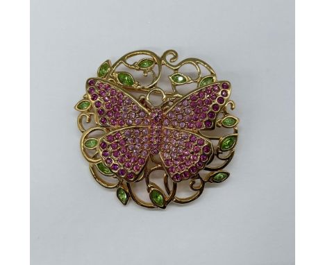 This stunning gold-toned rhodium piece features green crystal leaves and a butterfly adorned with pink crystals, gracefully s