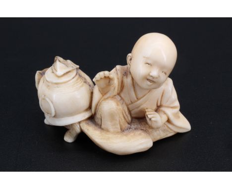 A Japanese ivory netsuke of a child sitting with a small animal, 4 cm
