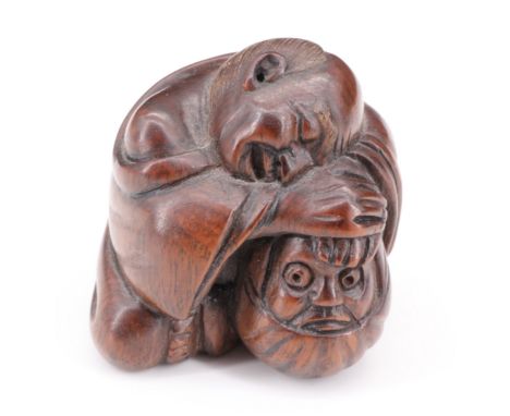 A Japanese carved wood netsuke of a man sleeping against a Daruma doll, 4 cm