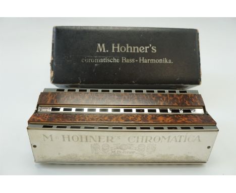 A cased Hohner "Chromatische" brass harmonica